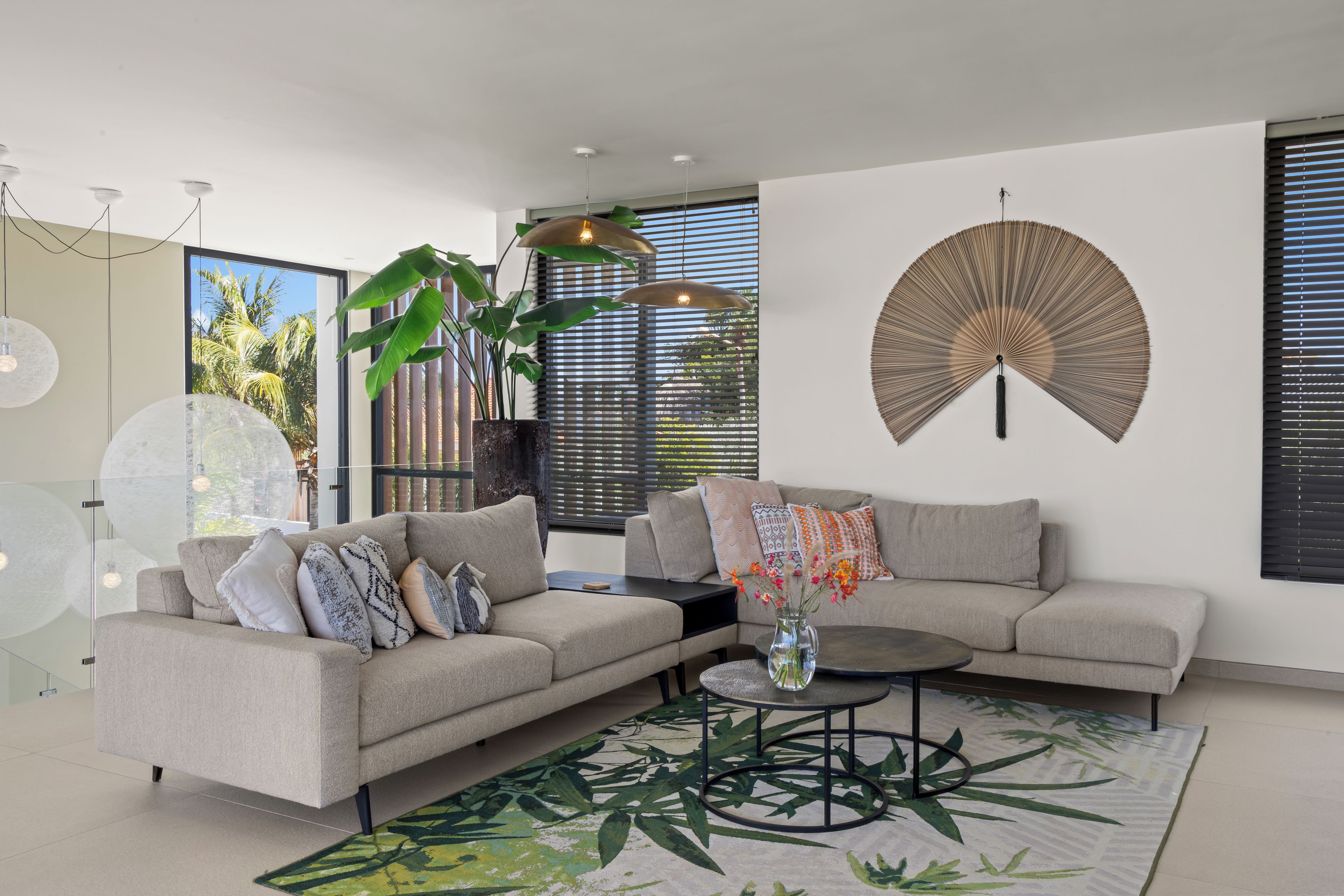 Un salon moderne avec un canapé, une table basse et un grand ventilateur décoratif.