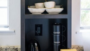 Een keuken met planken vol keukengerei, een koffiezetapparaat en een boek.
