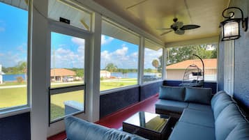 A covered porch with a sofa, a table, and a ceiling fan.