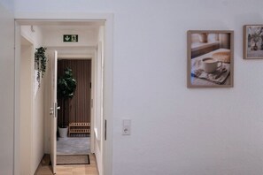 A hallway with a door leading to a room, a potted plant, and a framed picture on the wall. - Fireside by Loftigo - Terrace, Garden & Fireplace (Übach-Palenberg)