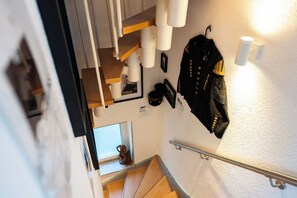 A staircase with a handrail, a wall-mounted coat rack with a jacket, and a small decorative item on the landing. - Fireside by Loftigo - Terrace, Garden & Fireplace (Übach-Palenberg)