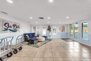 Een hotel lobby met een blauw-wit kleurenschema, een bank, een bijzettafeltje, een plant en een bordje met de tekst 'Sea Oats'.