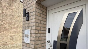 Une porte avec une poignée en métal et un panneau de verre, un mur de briques et une pancarte sur laquelle on peut lire : « HAVRE DE PAIX ».