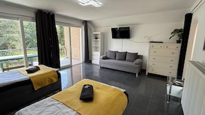A modern hotel room with two beds, a sofa, a TV, and a view of the outdoors. - Garden Retreat by Loftigo - Balcony & Natural Serenity (Selfkant)