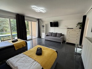 Een moderne hotelkamer met twee bedden, een bank, een televisie en uitzicht op de omgeving.
