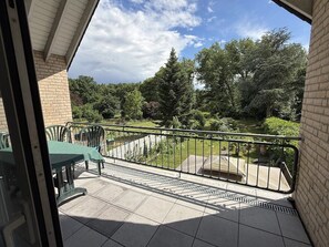 Een balkon met uitzicht op een tuin en bomen.