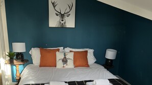 A bed with a plaid bedspread, two pillows, and a wall-mounted deer painting. - Exclusive Apartment at Historic Hall With Hard Tennis Court (Tadcaster)