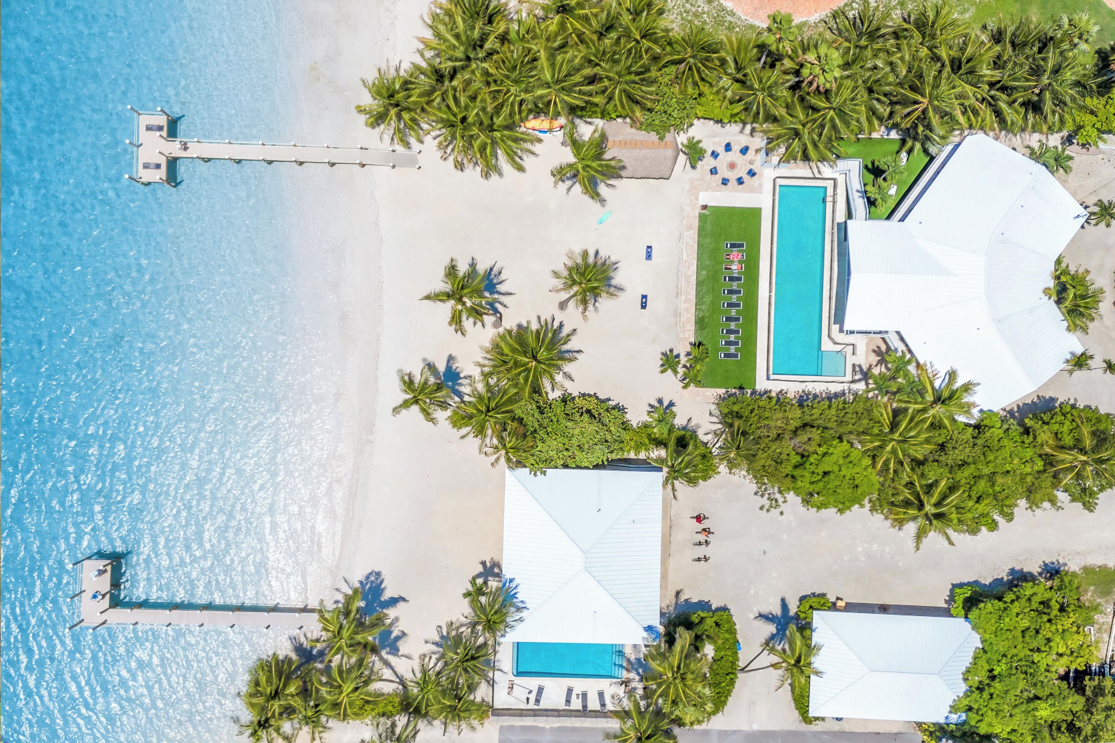 Vista aerea di un resort con piscina, spiaggia e palme.