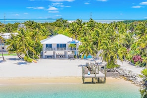 A beachfront property with a white building, palm trees, and a clear view of the ocean. - Beachfront Estate - Two Villas / Heated Pools / Docks / Dolphin & Mahi Key (Islamorada)