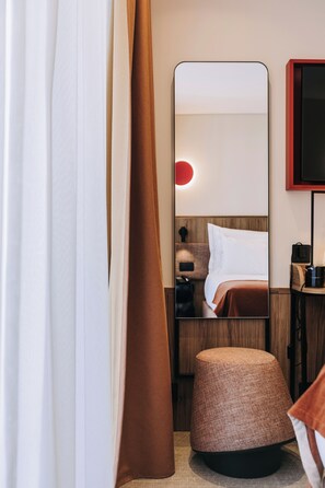 A hotel room with a bed, a bedside table, a mirror, a red wall light, and a brown curtain. - 705 O'Porto Hotel (Porto)