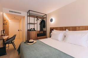 A hotel room with a bed, a desk, a chair, a wardrobe, and a hanging clothes rack. - 705 O'Porto Hotel (Porto)