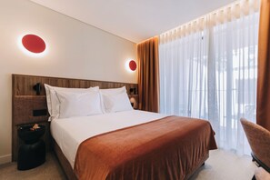 A hotel room with a bed, a nightstand, a chair, and a window with curtains. - 705 O'Porto Hotel (Porto)