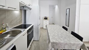 A modern kitchen with white cabinetry, a stainless steel sink, a microwave, and a dining table with chairs. - Larnaca Sunset One-bedroom Suite Close to the Beach (Larnaca)