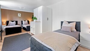 A modern bedroom with two beds, a wardrobe, a bedside table, and a small plant. - Oasis by Loftigo - Cozy Apartment with Rain Shower (Selfkant)