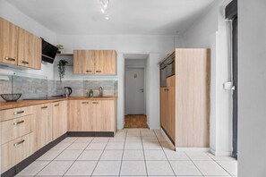 A modern kitchen with wooden cabinets, a tiled backsplash, and a black range hood. - Forest by Loftigo - Patio & Sunroom (Selfkant)