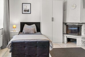 Ein Schlafzimmer mit Bett, Nachttisch, Lampe, Kleiderschrank und Kamin.