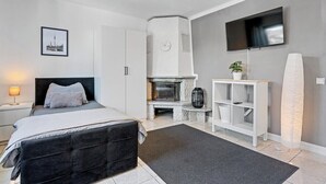 Quarto moderno com cama, lareira, TV e uma prancha de surf.