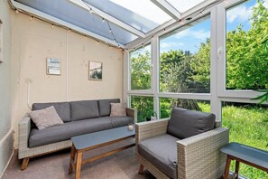 Ein sonnendurchflutetes Zimmer mit einer Couch, einem Sessel und einem Couchtisch.