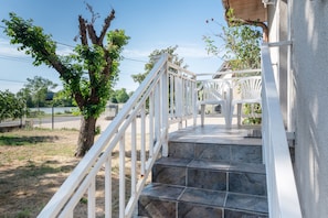 A staircase with white railings leading to a covered outdoor area with a view of a road and trees.