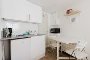 A compact kitchenette with a coffee maker, microwave, and storage cabinets. - Cozy Studio Escape by Clapham Common (Greater London)