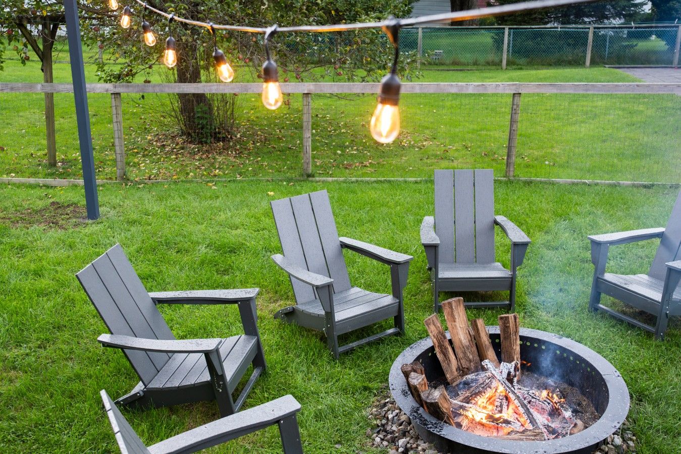 Un espace extérieur aménagé avec des chaises Adirondack et un foyer.
