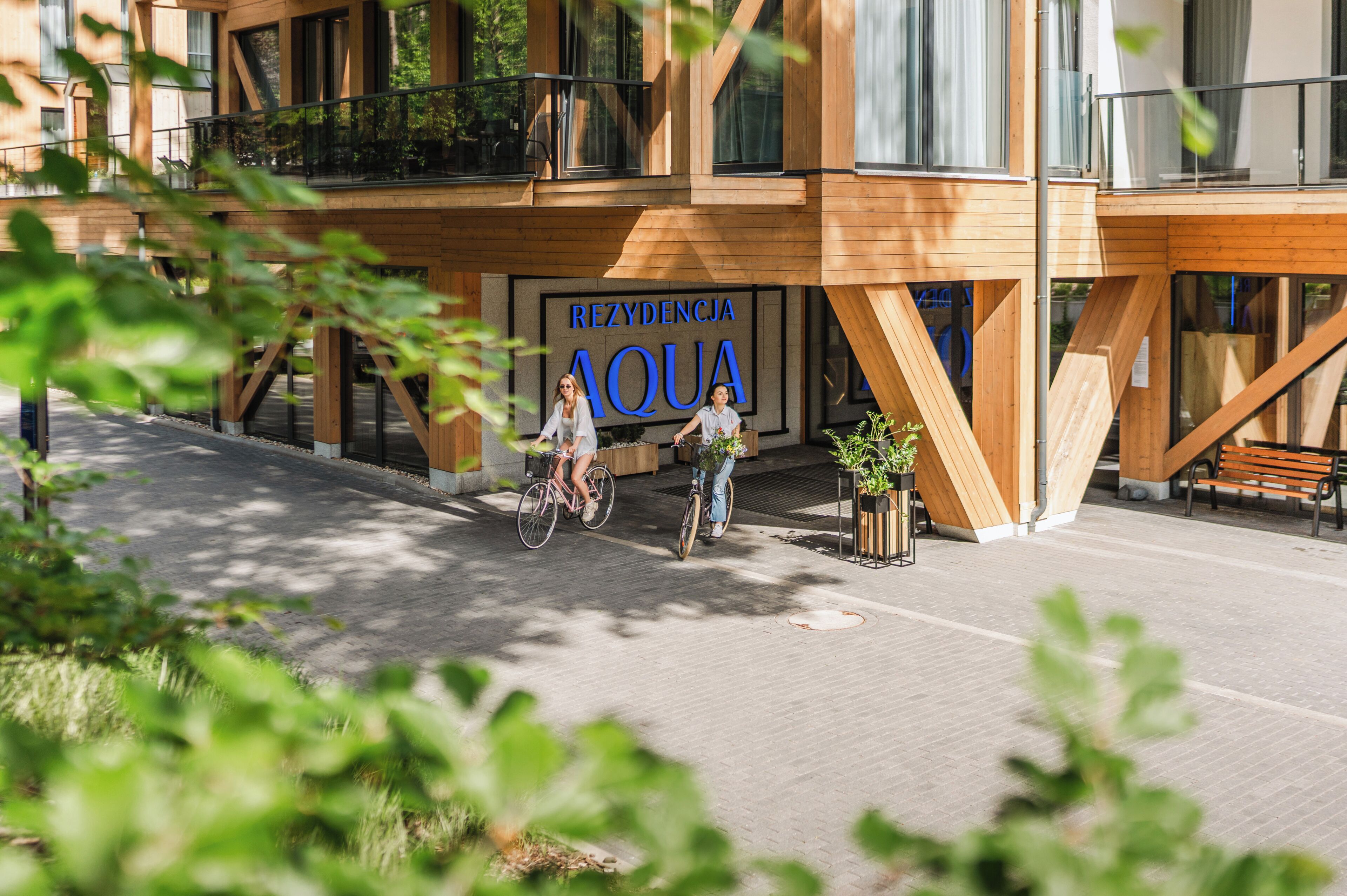 A modern building with a wooden facade and a sign that reads 'REZYDENCJA AQUA'.