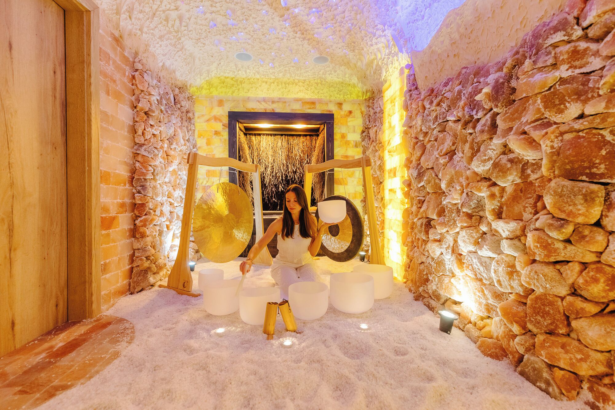 Un cuarto de spa con pared de piedra, puerta de madera y camilla de masaje.