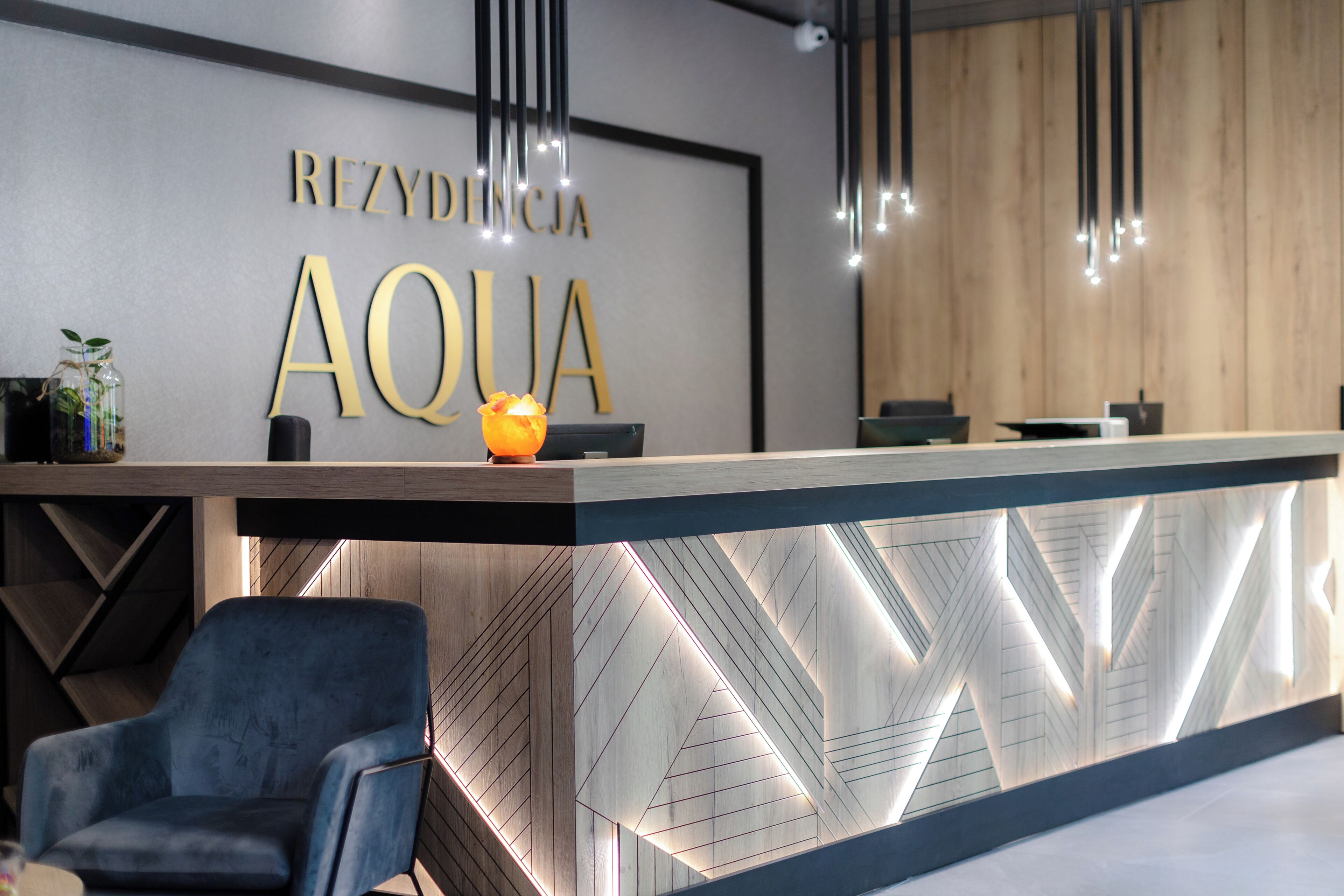 A reception desk with a modern design, featuring a wooden panel and geometric light patterns.