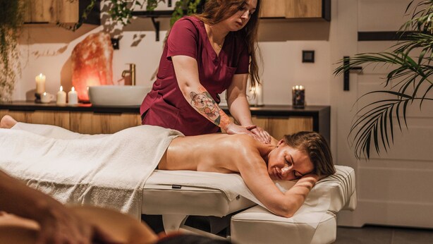 En massagebehandling i ett rum med modern design, inklusive ett träskåp och en växt.