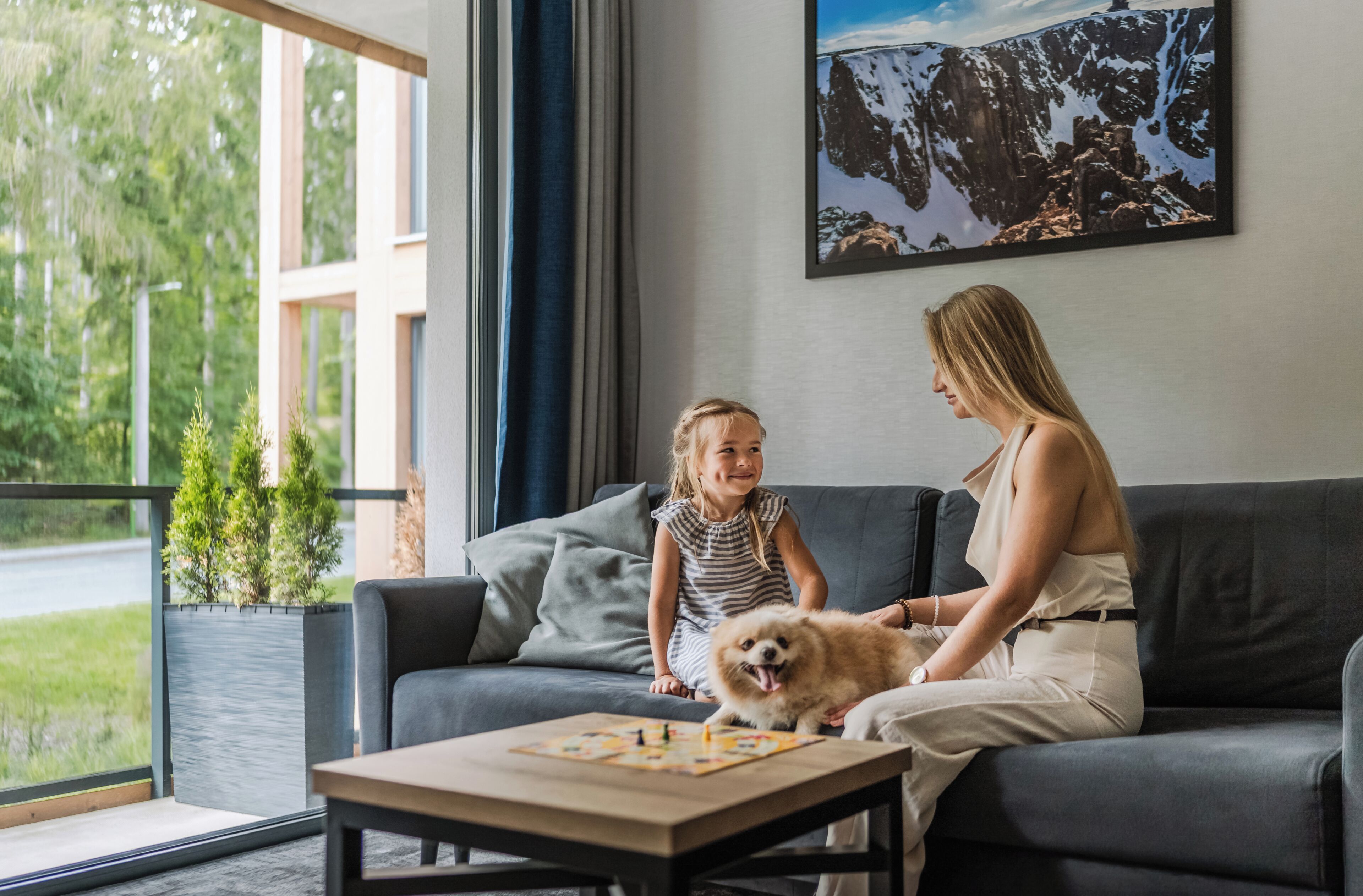 A modern living room with a sofa, a coffee table, and a window with a view of greenery.