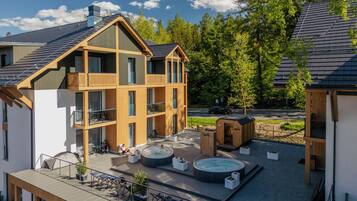 A multi-story building with a rooftop terrace, hot tubs, and a wooden deck.