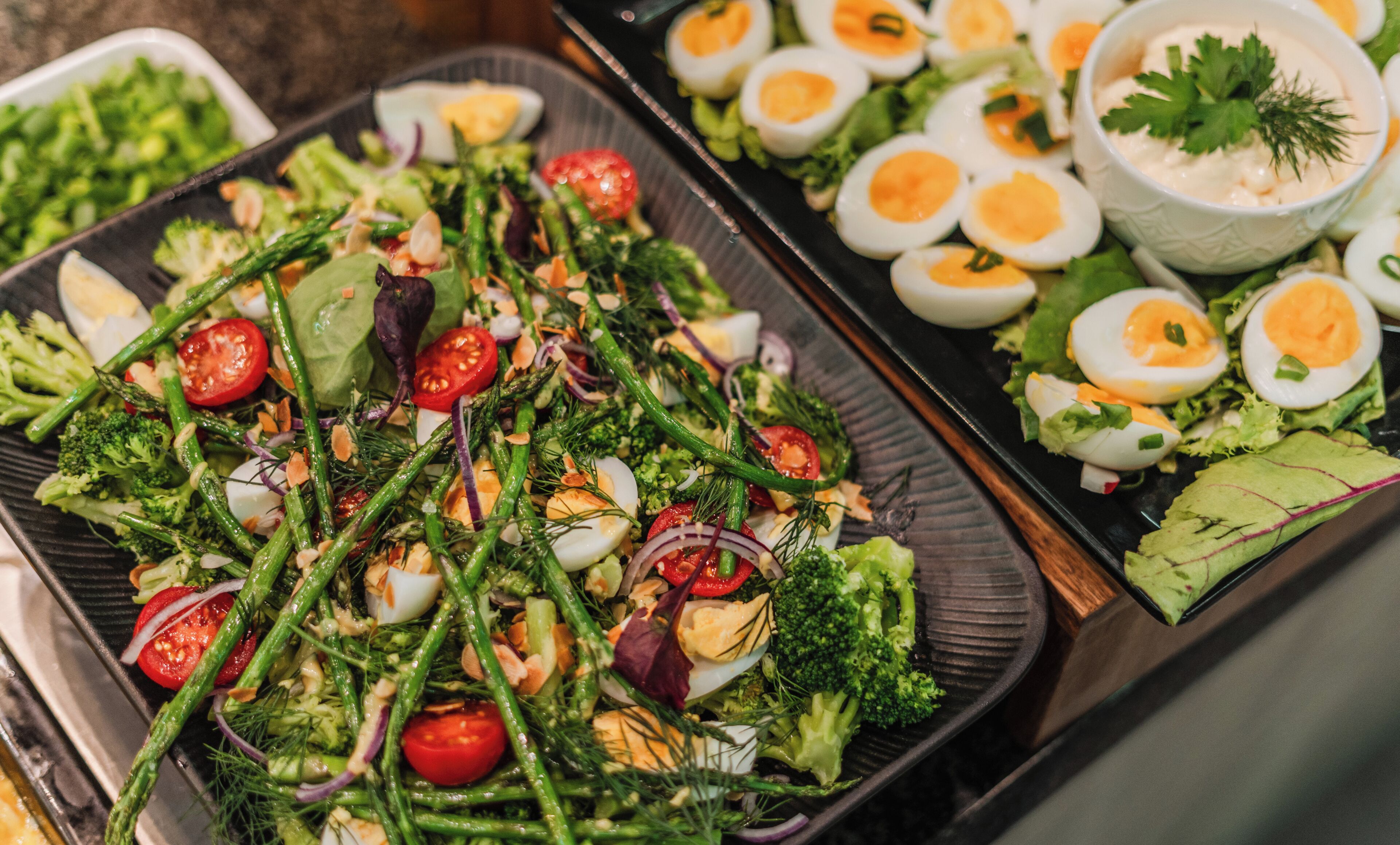 A buffet with various dishes including a salad with vegetables and eggs.