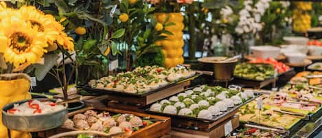 A buffet with various food items, including salads, meats, and desserts, arranged on wooden boards.