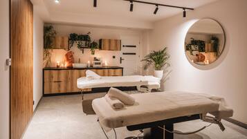 Un moderno spa con camilla de masaje, armarios de madera y un espejo.