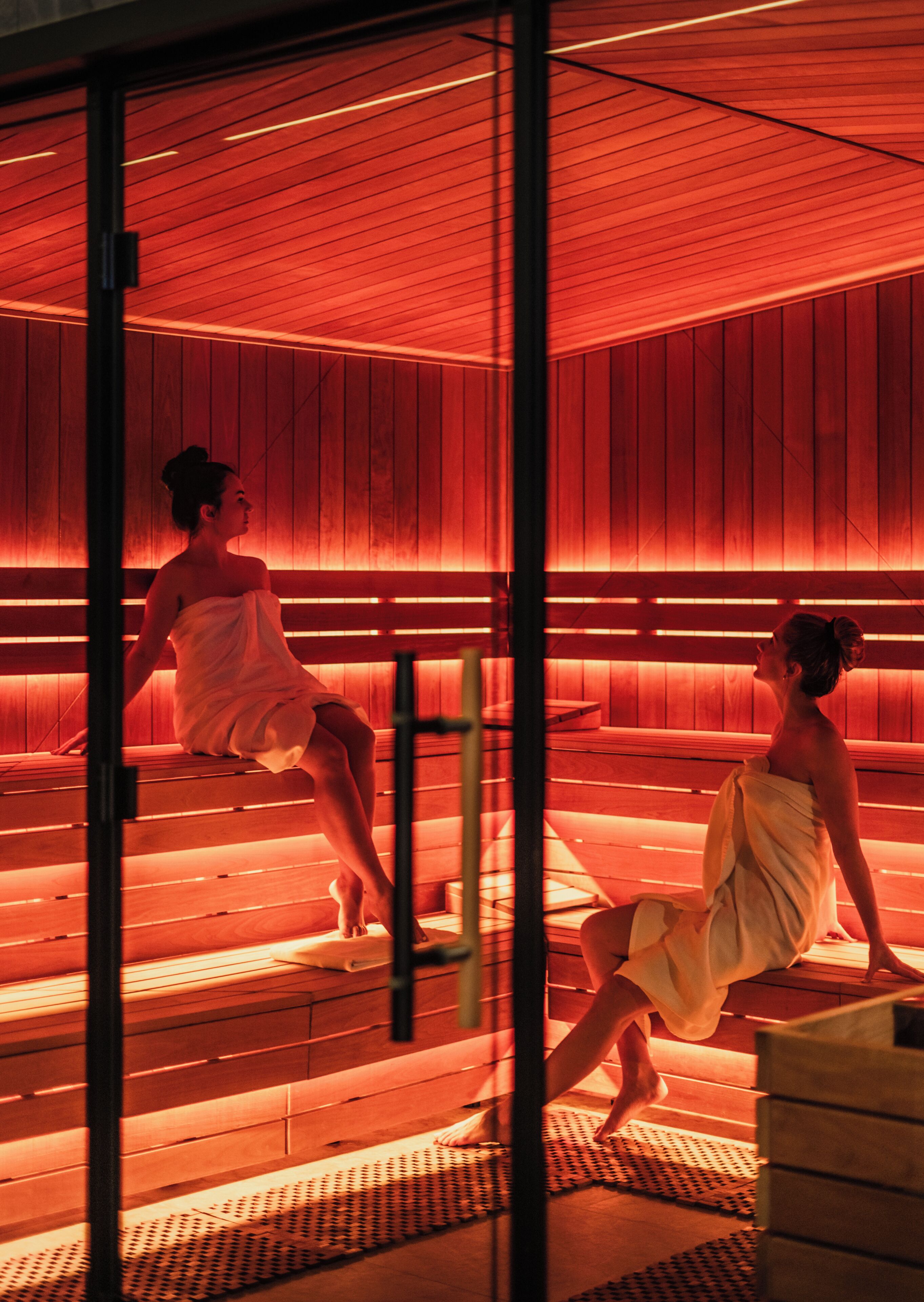 Uma sauna com bancos de madeira e chão de azulejos.