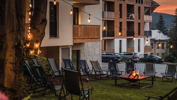 Un edificio moderno con varios balcones, mobiliario de exterior y una chimenea.