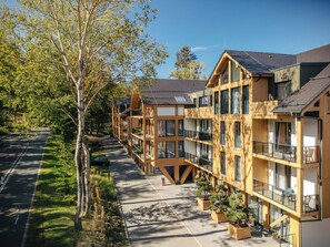 A modern multi-story building with balconies, large windows, and a central courtyard with potted plants.