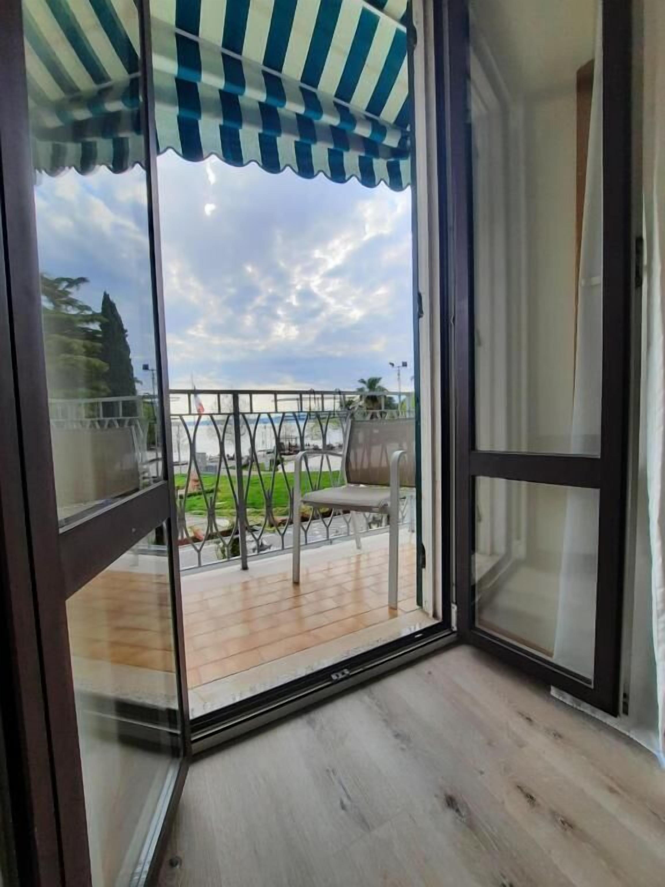 Una stanza con una porta scorrevole in vetro che dà su una terrazza esterna con vista sul cielo e sul paesaggio circostante.