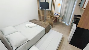 Ein Hotelzimmer mit Bett, Schreibtisch, Fernseher und einem kleinen Tisch mit Stuhl.