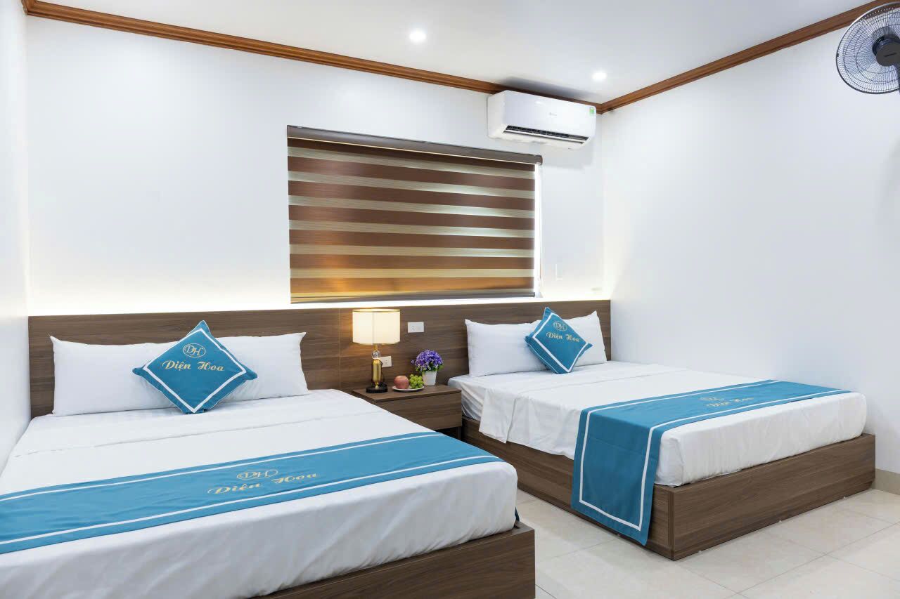 Ein Hotelzimmer mit zwei Betten, einem Nachttisch, einer Klimaanlage und einem Fenster mit Jalousien.