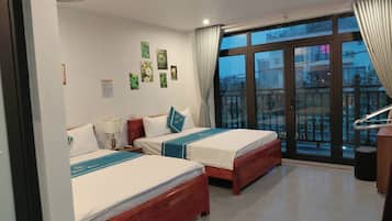 A hotel room with two beds, a balcony with a view, and a wooden floor.