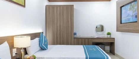 A hotel room with two beds, a desk, a chair, a nightstand, and a wall-mounted TV.