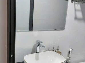 A bathroom with a white sink, a mirror, and a towel rack.