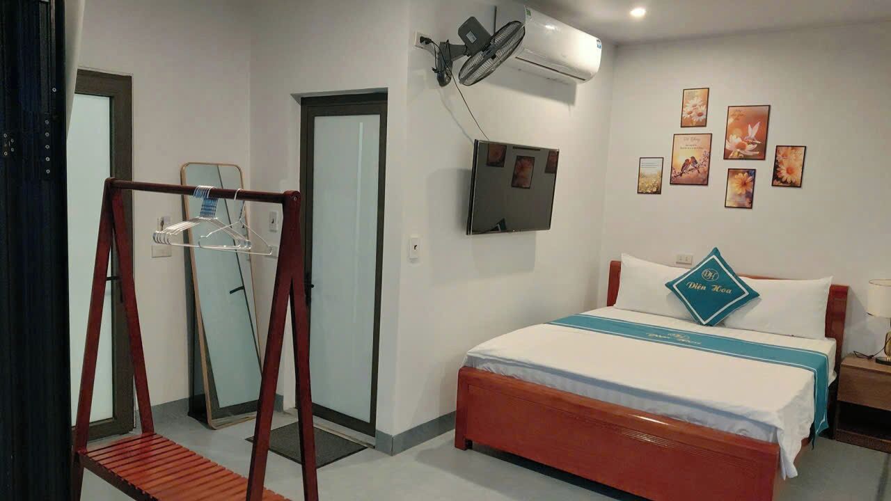 A hotel room with a bed, a wall-mounted air conditioner, a mirror, and a door.