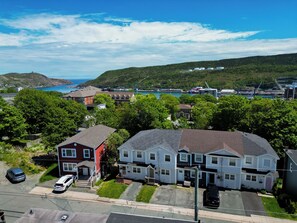 A residential area with houses, a parking lot, and a view of a harbor with boats. - Welcome to The Crossing, a thoughtfully restored 3-bedroom home on a quiet residential street in historic St. John's. Enjoy free off-street parking, a private fenced yard, and all the comforts of home—just minutes from the best of St. John's. (St. John's)
