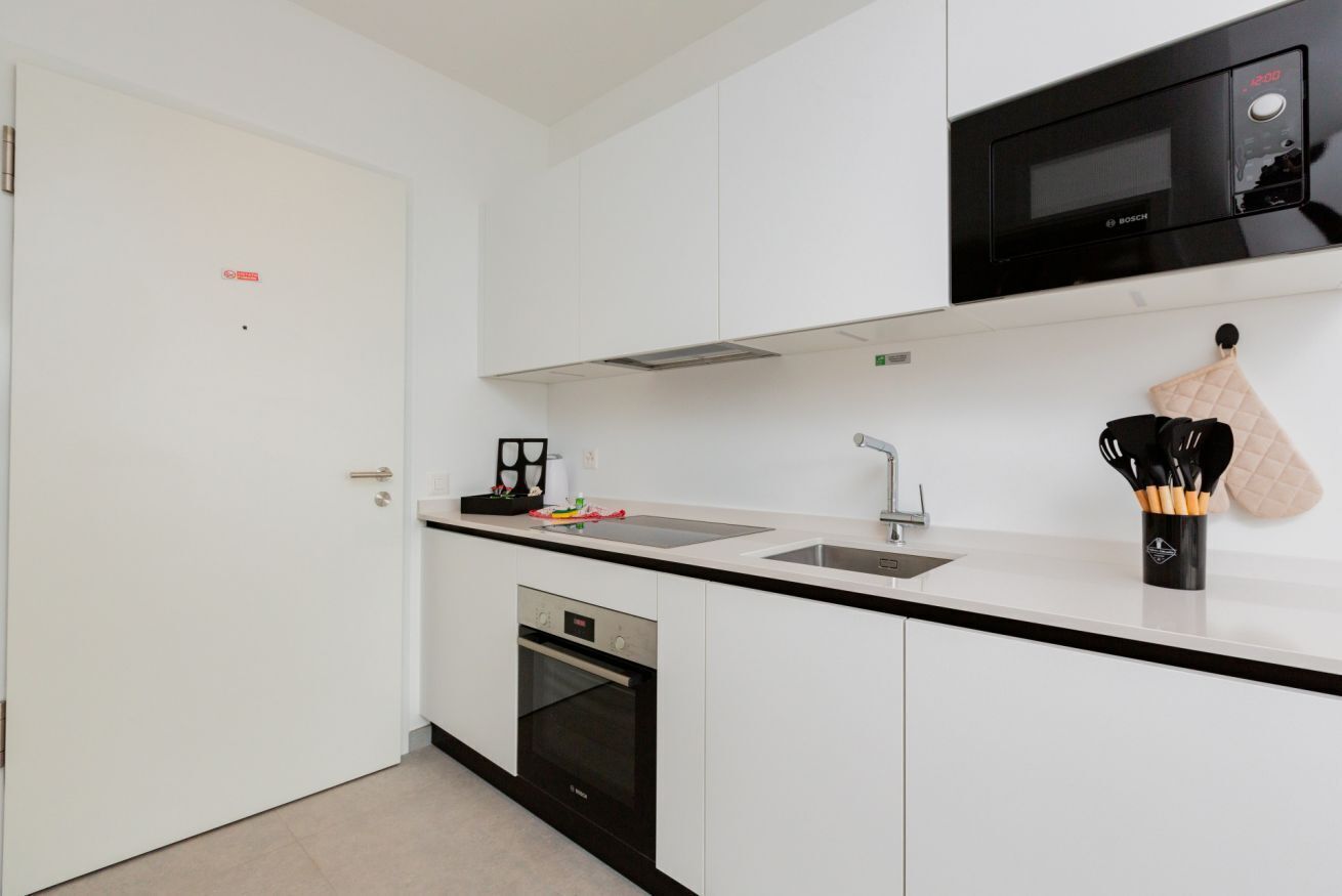 Eine moderne Küche mit einer Bosch-Mikrowelle, einem Backofen, einer Spüle und einer Arbeitsplatte mit Küchenutensilien.