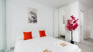 Ein modernes Hotelzimmer mit einem großen Bett, einem Spiegel, einer Zimmerpflanze und Bildern an der Wand.