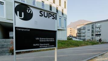 Ein Schild mit der Aufschrift 'SUPSI Campus Est', im Hintergrund ein modernes Gebäude.