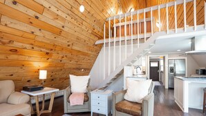 A wooden interior with a staircase, a kitchen, and a seating area with a rug. - Ridge And Pine Retreat: Long-Stay Lodging, Private Hot Tub (Breckenridge)