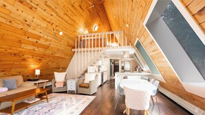 A loft-style interior with a wooden ceiling, a dining area, a staircase, and a large window. - Ridge And Pine Retreat: Long-Stay Lodging, Private Hot Tub (Breckenridge)